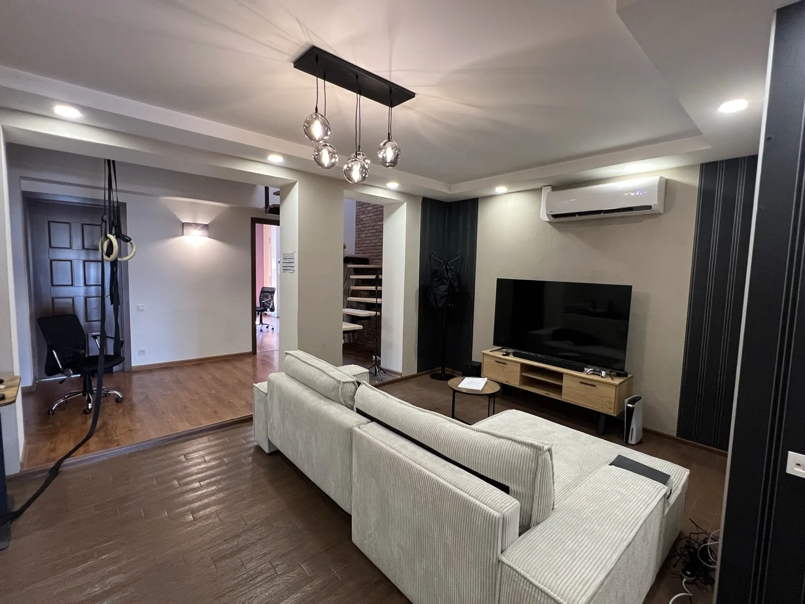 Living room with sofa, TV, and floating staircase